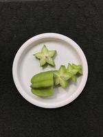 Green star fruit slices on a pink plastic plate photo