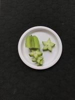 Green star fruit slices on a pink plastic plate photo