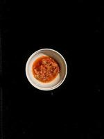 Chili sauce in a white container photo