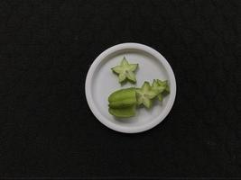 Green star fruit slices on a pink plastic plate photo