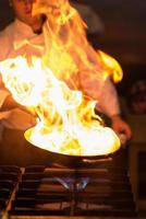 chef haciendo flambeado en la comida foto