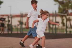 A little girl and brother in modern summer clothes playing in the park in summer. Selective focus photo