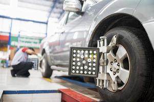 Professional mechanic near wheel center, wheel alignment, mounted on each tire for driving center. Wheel alignment in the garage photo