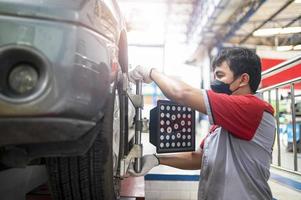 Professional mechanic near wheel center, wheel alignment, mounted on each tire for driving center. Wheel alignment in the garage photo