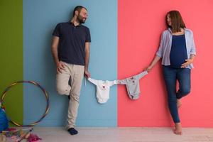 young couple holding baby bodysuits photo