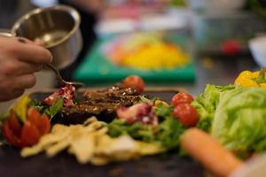 Chef finishing steak meat plate photo