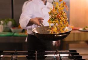 chef flipping vegetables in wok photo