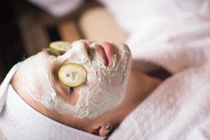 woman is getting facial clay mask at spa photo