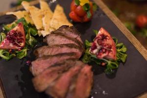 Juicy slices of grilled steak on wooden board photo