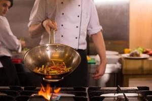 chef flipping vegetables in wok photo