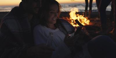 Couple enjoying bonfire with friends on beach photo