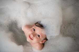 top view of little girl in bath playing with foam photo