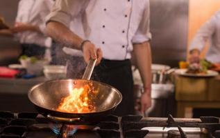 chef haciendo flambeado en la comida foto