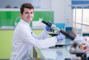 estudiante científico mirando a través de un microscopio foto