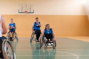 veteranos de guerra discapacitados de raza mixta que se oponen a equipos de baloncesto en sillas de ruedas fotografiados en acción mientras juegan un partido importante en una sala moderna. foto