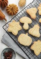 Cookies shaped like pumpkin and leaves on rustic wood background photo