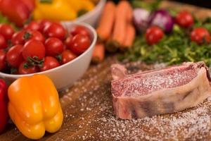 Juicy slice of raw steak on wooden table photo