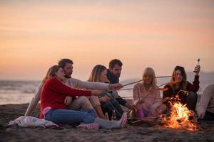 Group Of Young Friends Sitting By The Fire at beach photo