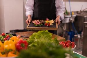 female Chef holding beef steak plate photo