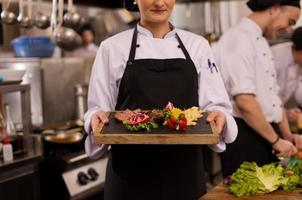 female Chef holding beef steak plate photo