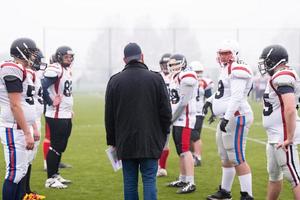 jugadores de fútbol americano discutiendo estrategia con el entrenador foto