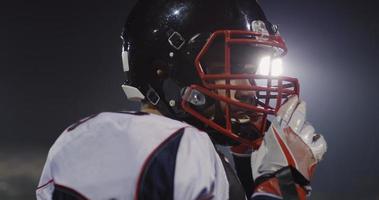 American Football Player Putting On Helmet on large stadium with lights in background photo