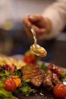 Chef finishing steak meat plate photo