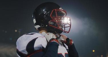 jugador de fútbol americano poniéndose el casco en un gran estadio con luces de fondo foto