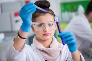 female student with protective glasses making chemistry experiment photo