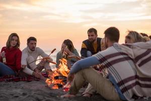 Group Of Young Friends Sitting By The Fire at beach photo