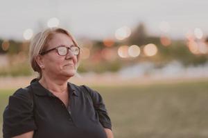 Portrait of an elderly woman with blonde hair and glasses on the beaches of the Mediterranean Sea at sunset. Selective focus photo