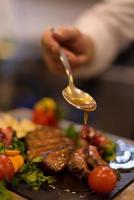 Chef finishing steak meat plate photo