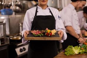 female Chef holding beef steak plate photo