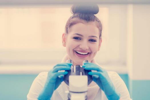 female student scientist looking through a microscope photo