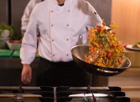 chef flipping vegetables in wok photo