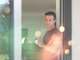 man drinking coffee in front of her luxury home villa photo