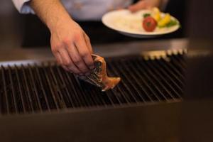 chef manos cocinando salmón a la parrilla foto