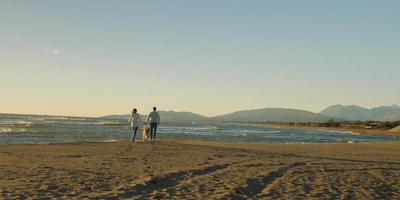 couple with dog having fun on beach on autmun day photo