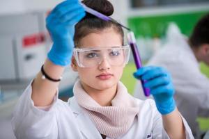 female student with protective glasses making chemistry experiment photo