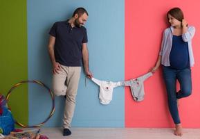 young couple holding baby bodysuits photo