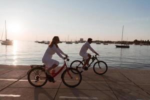 Senior couple enjoying a beautiful morning together riding a bike by the sea. Selective focus photo