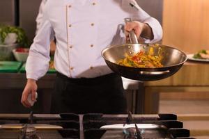 chef flipping vegetables in wok photo