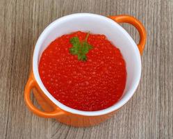 Red caviar in a bowl on wooden background photo