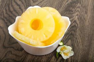 Canned pineapple in a bowl on wooden background photo