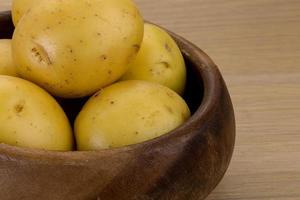 Raw potatoes in a bowl on wooden background photo