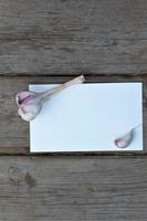 garlic and garlic cloves on a white sheet with space for writing on a wooden background photo