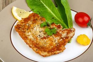 Pork schnitzel on the plate and wooden background photo