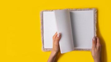 Hand hold notebook empty spread on yellow background,banner photo