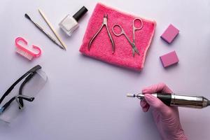 A manicurist in gloves holds a nail drill. photo