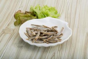 Dries anchovy in a bowl on wooden background photo